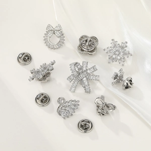 Detailed view of 10pcs silver bow and flower crystal brooch set on white silk fabric
