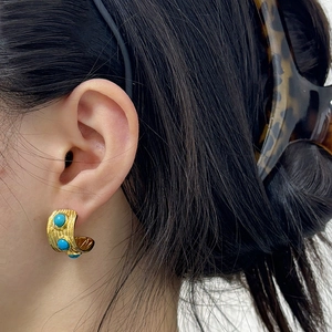 Orecchini retrò dorati a forma di C con texture e pietre turchesi indossati da modella
