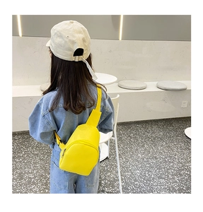 Toddler girl wearing a bright yellow PU leather crossbody bag over a denim jacket