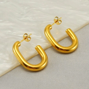 Elegant gold U-shaped hoop earrings with a high-polished finish on marble background