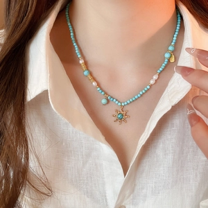 Détail du collier pendentif soleil avec perles de turquoise et perles sur lin