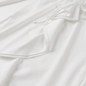Détail d'une robe blanche montrant les volants et la texture du tissu à nouer