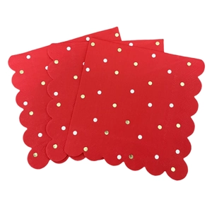 Red Christmas paper napkins with gold polka dots and scalloped edges on white background