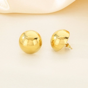 Macro detail of polished gold half-ball stainless steel stud earrings for women