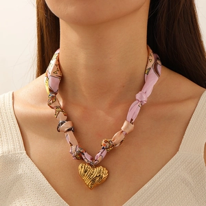 Detail of pink floral ribbon chain necklace with gold heart pendant worn by model