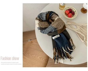 Close-up of checkered scarf with long tassels and Superwoman label on a table