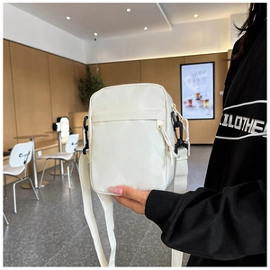 Close-up of minimalist white canvas crossbody bag with adjustable strap for men