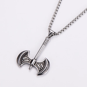 Close-up of a silver battle axe pendant with intricate Viking carvings and a sturdy link chain
