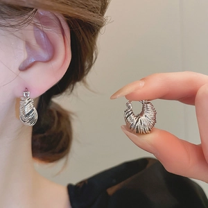 Detail view of silver twisted croissant hoop earrings with model wearing for scale