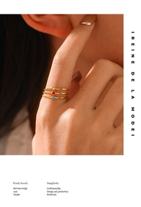 Close-up of three dainty gold rings featuring vibrant yellow, red, and blue birthstones