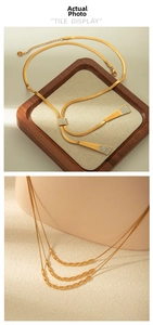 Detail of gold snake chain necklace with Y-shaped tassel and geometric diamond pendant
