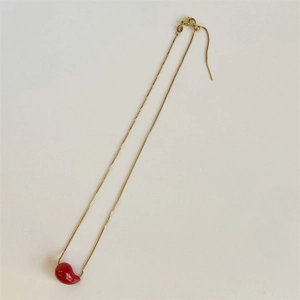 Close-up of a polished red drop pendant on a delicate gold stainless steel chain
