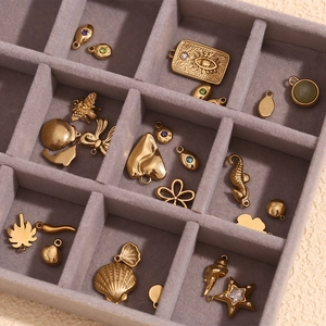 Detailed close-up of 14K gold plated shell, seahorse, and star charms in a velvet tray