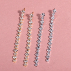 Detail of long tassel earrings in gold and silver finish with square cubic zirconia