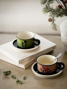 Detailed view of hand-painted floral ceramic coffee cups with matching black saucers