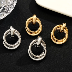 Macro shot of gold and silver interwoven triple hoop earrings on black fabric background
