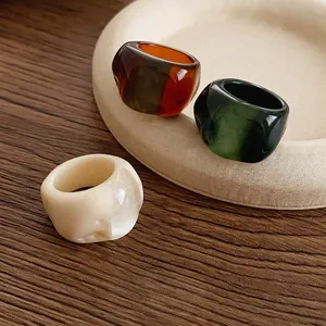 Retro resin rings in marbled cream white, amber brown, and emerald green on display