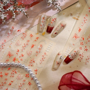 Detailed view of Chinese style butterfly and floral nail stickers on burgundy manicured nails