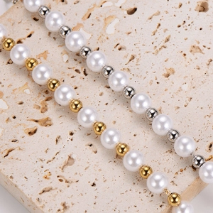 Minimalist pearl bracelet with gold and silver beads displayed on a stone background
