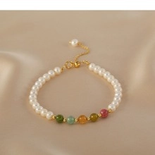 Detail of freshwater pearls and colorful gemstones on a gold adjustable bracelet