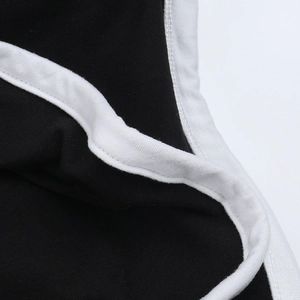 Detailaufnahme von schwarzem Strickstoff mit weißer Paspelierung und präziser Nahtführung