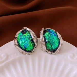 Macro shot of vintage silver earrings with green resin stone and sparkling rhinestones