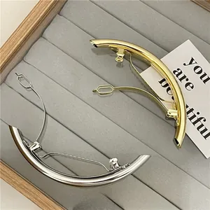 Polished gold and silver crescent hair clips on a velvet jewelry tray close-up view