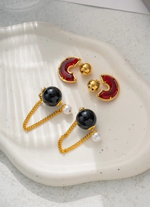 Detail von eleganten schwarzen Kugelohrringen mit Goldkette und Perlenquaste auf Tablett