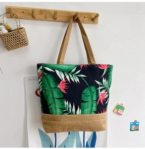 Canvas tote bag with green banana leaf pattern hanging on a wooden hook detail