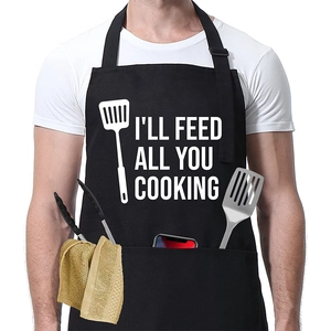 Detail der schwarzen Schürze mit weißem Text I'LL FEED ALL YOU COOKING und Tasche