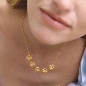 Détail du collier marguerite doré avec cinq breloques en zircon sur le cou