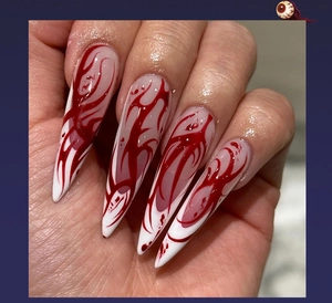 Detail of long stiletto press-on nails with white base and red blood drip pattern