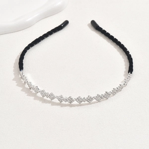 Elegant black velvet headband with sparkling silver rhinestone diamonds on beige texture
