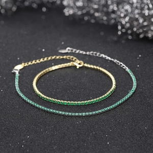Macro shot of silver and gold tennis bracelets with vibrant green stones and lobster clasp