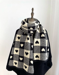 Detail view of the black and white checkered knit scarf with woven heart patterns on a mannequin