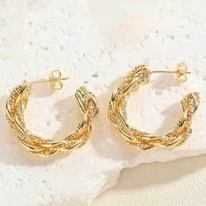 Macro view of 14K gold plated twisted hoop earrings on white marble stone