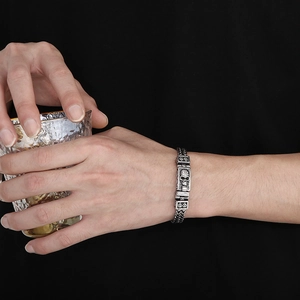 Detailed view of silver skull bracelet with vintage metal texture and double-chain design