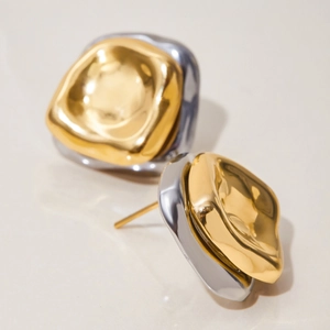 Détail macro de boucles d'oreilles bicolores or et argent à texture de lave irrégulière