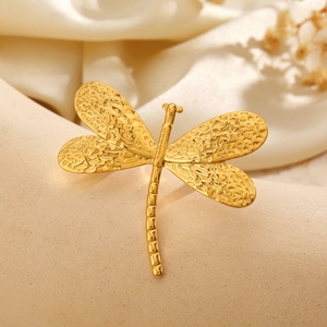 Elegant gold dragonfly ring with textured metallic finish on soft white silk background
