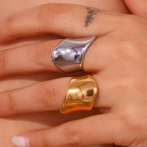 Close-up of wide irregular flowing metallic rings in gold and silver finishes