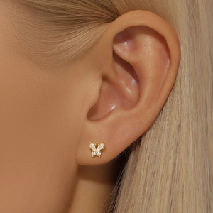Detail of gold butterfly stud earring with sparkling zircon on model ear cartilage