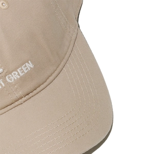 Detailed close-up of white letter GREEN embroidery and stitching on khaki cotton baseball cap
