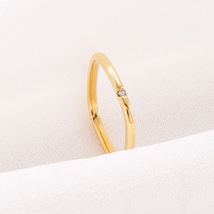 Detail of minimalist gold square ring featuring a delicate round diamond on fabric