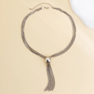 Close-up of silver multilayer punk chain necklace featuring a round bead and long tassels