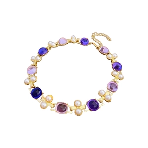 Bracelet vintage doré avec pierres violettes et perles sur un fond blanc épuré et chic