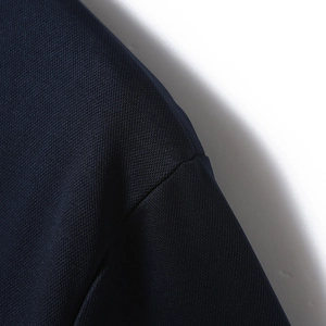 Close-up of navy blue golf polo shirt showing fine twill texture and seam stitching detail