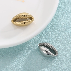 Minimalist gold and silver stainless steel shell pendants displayed on ceramic surface