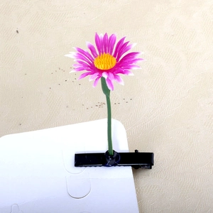 Detail of purple flower hair clip with yellow stamen on a classic metal alligator base