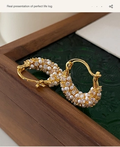 Detail of vintage gold-plated hoop earrings with micro-set pearls and zircons in a wooden box
