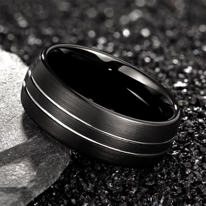 Men's black tungsten ring with brushed surface and silver grooves on textured stone